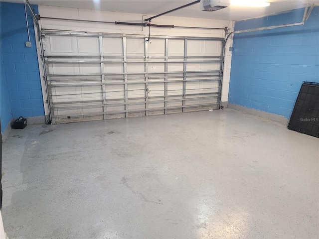 garage with a garage door opener and concrete block wall