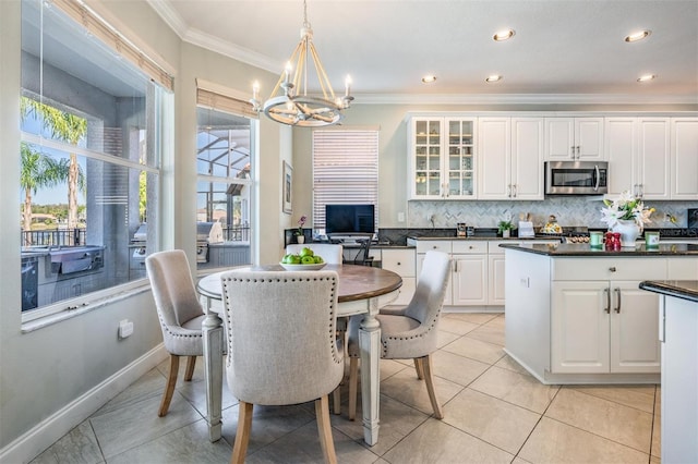17927 Bahama Isle Cir, Tampa, FL 33647 - kitchen with decorative backsplash, stainless steel microwave, white cabinets, a notable chandelier, and crown molding