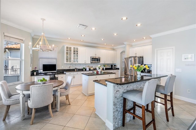 17927 Bahama Isle Cir, Tampa, FL 33647 - kitchen featuring an inviting chandelier, appliances with stainless steel finishes, dark countertops, visible vents, and a center island with sink
