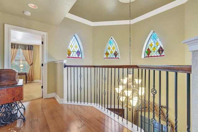 hallway with wood-type flooring, healthy amount of natural light, ornamental molding, and baseboards