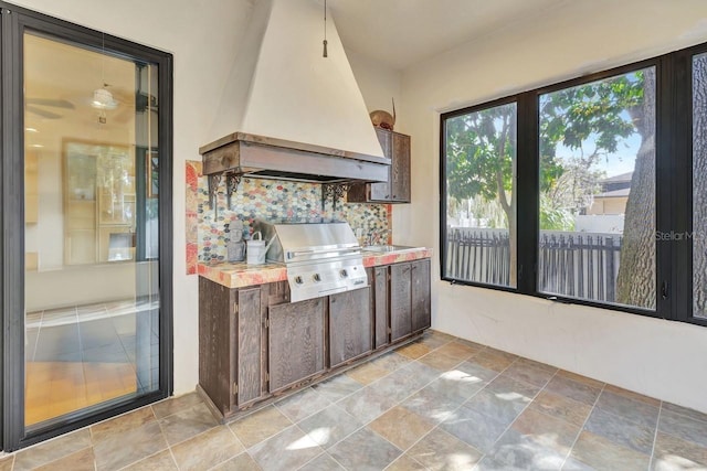 1108 W Charter St, Tampa, FL 33602 - kitchen with custom exhaust hood, light countertops, backsplash, stone finish floors, and dark brown cabinets