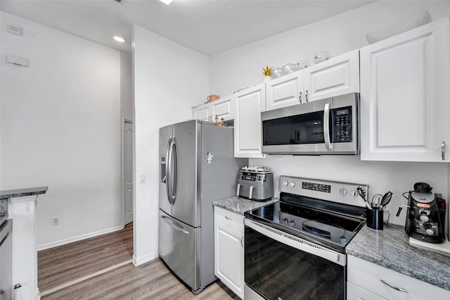 8528 Quarter Horse Dr, Riverview, FL 33578 - kitchen with stainless steel appliances, light wood finished floors, light stone countertops, and white cabinets