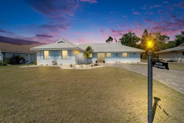ranch-style home featuring decorative driveway, a front lawn, and a tile roof