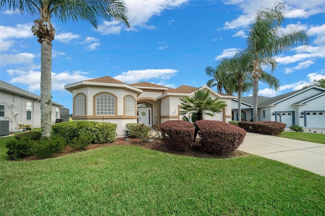 mediterranean / spanish home with stucco siding, a front lawn, driveway, cooling unit, and a garage