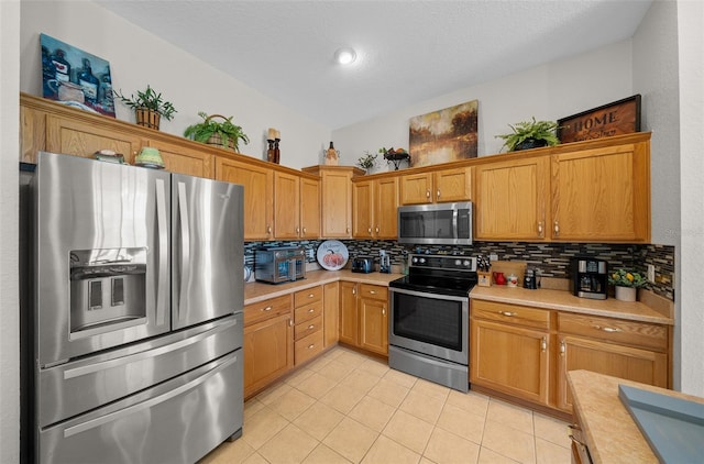 kitchen featuring light tile patterned floors, decorative backsplash, stainless steel appliances, and light countertops