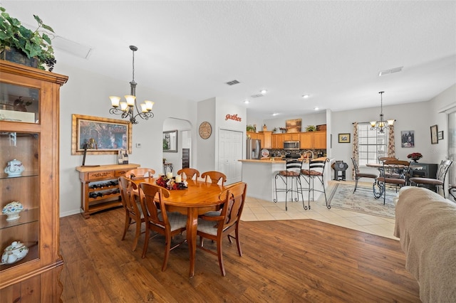 dining area featuring a notable chandelier, arched walkways, and visible vents