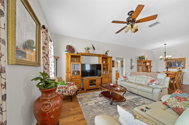 living area featuring visible vents, light wood-style flooring, and ceiling fan with notable chandelier