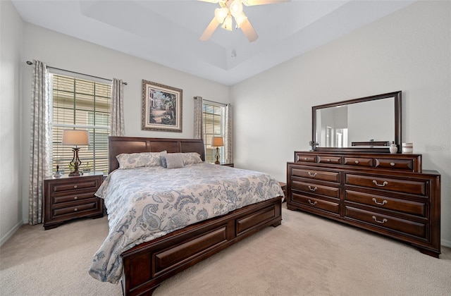 bedroom featuring a tray ceiling, light carpet, and a ceiling fan