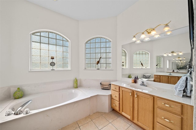 bathroom with a wealth of natural light, a garden tub, vanity, and tile patterned flooring