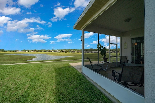 view of yard featuring a sunroom and a water view