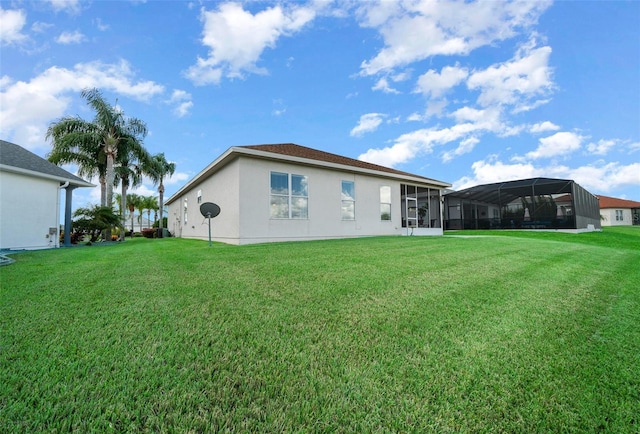 back of house with stucco siding, a lawn, and a sunroom