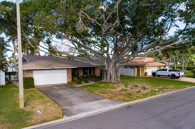 ranch-style home featuring driveway, an attached garage, a front lawn, and brick siding