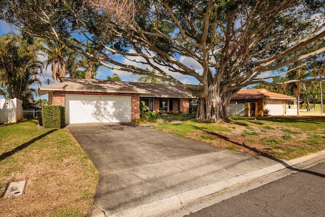 view of front of house featuring concrete driveway, fence, a front lawn, brick siding, and a garage