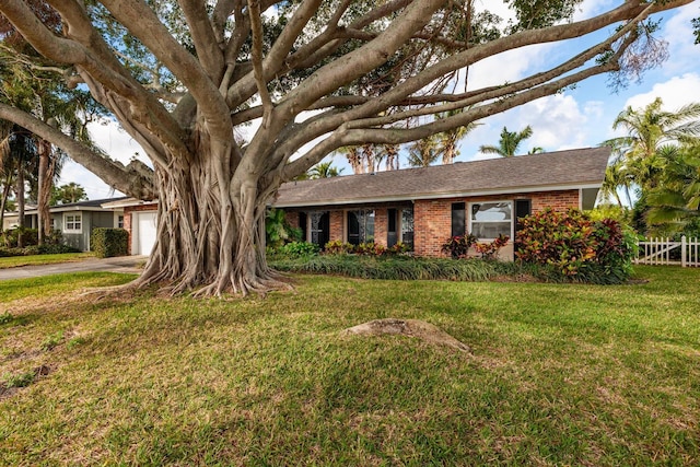 ranch-style house with driveway, brick siding, a front lawn, and an attached garage