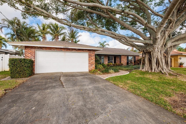ranch-style home with driveway, a front yard, a garage, and brick siding