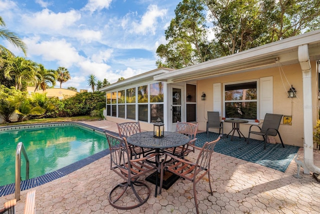 view of pool with outdoor dining space, a sunroom, a patio, and a fenced in pool