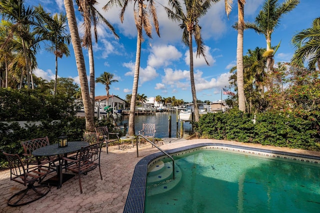 view of swimming pool with a water view, a patio, and a dock