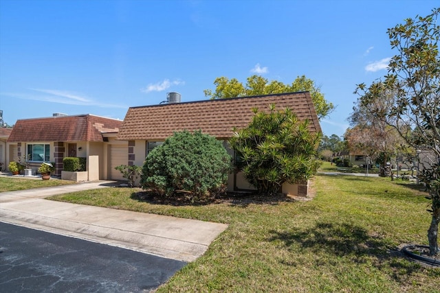 8445 Calais N, Pinellas Park, FL 33781 - view of front facade with mansard roof, a front lawn, an attached garage, stucco siding, and concrete driveway