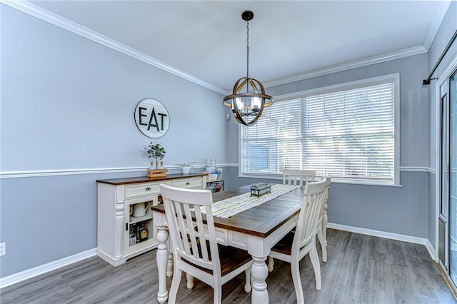 dining area featuring baseboards, ornamental molding, light wood-style flooring, and a chandelier