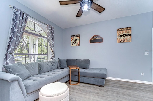 living room with a ceiling fan, baseboards, and light wood-type flooring