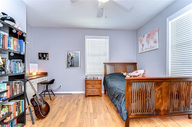 bedroom with multiple windows, wood finished floors, and baseboards