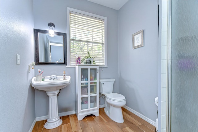 bathroom featuring baseboards, wood finished floors, and toilet