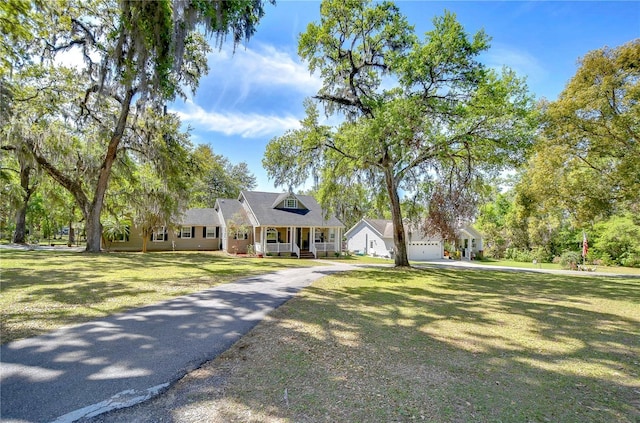 view of front of house featuring driveway, a garage, a front lawn, and a porch