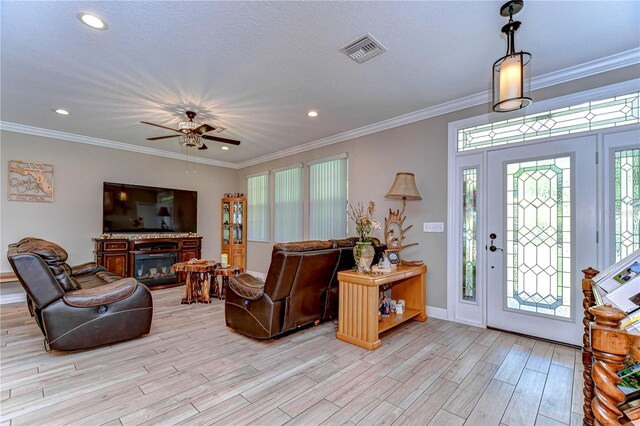 foyer entrance with a ceiling fan, light wood-style flooring, crown molding, and visible vents