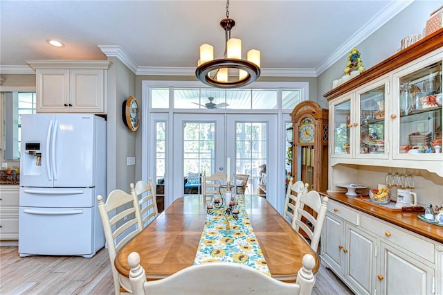 dining space featuring ornamental molding, a chandelier, french doors, and light wood finished floors