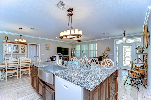 kitchen featuring a sink, light wood-type flooring, white dishwasher, brown cabinetry, and visible vents