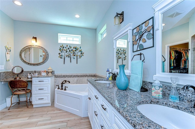 full bath with wood tiled floor, visible vents, double vanity, and a sink