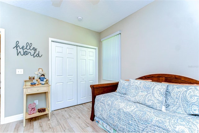 bedroom with a closet, baseboards, light wood-style flooring, and a ceiling fan