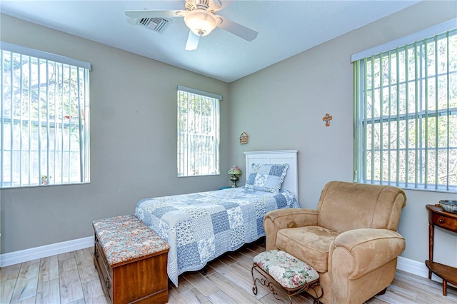 bedroom with baseboards, visible vents, light wood-style flooring, and a ceiling fan
