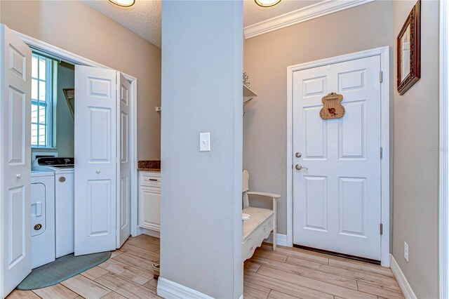 foyer with light wood-style flooring, independent washer and dryer, baseboards, and a textured ceiling