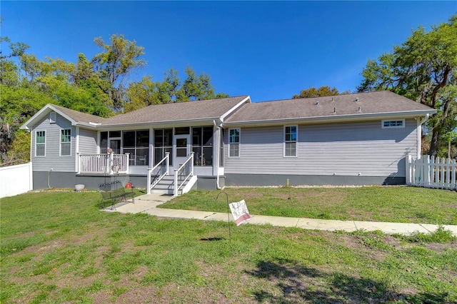 back of house with a sunroom, fence, and a yard