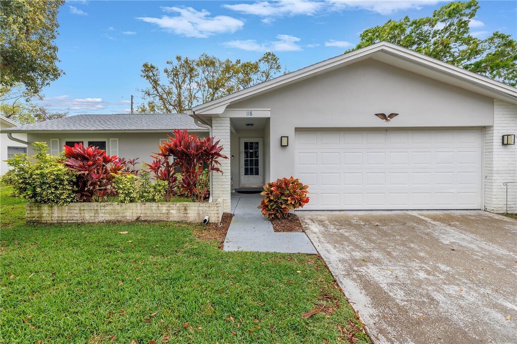 ranch-style house featuring an attached garage, a front lawn, driveway, and brick siding