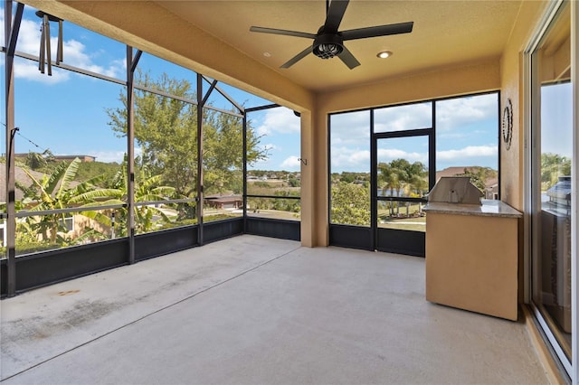 unfurnished sunroom featuring a ceiling fan and healthy amount of natural light