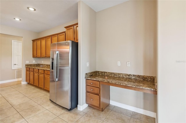 kitchen with stainless steel refrigerator with ice dispenser, brown cabinets, baseboards, and recessed lighting