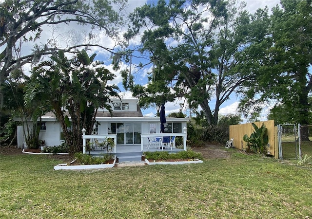 3204 W Clinton St, Tampa, FL 33614 - rear view of house featuring a gate, roof with shingles, fence, a sunroom, and a lawn