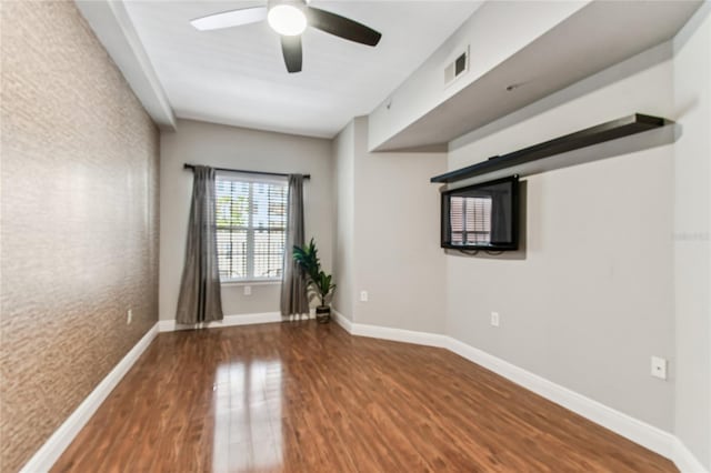 spare room featuring wood finished floors, visible vents, baseboards, and ceiling fan