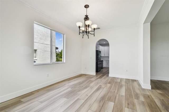 unfurnished dining area featuring arched walkways, light wood-type flooring, ornamental molding, a chandelier, and baseboards