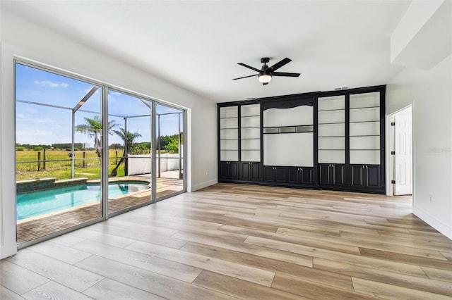 spare room featuring light wood-style floors, baseboards, and a ceiling fan