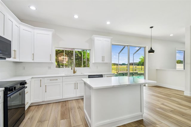 kitchen with a sink, light countertops, light wood-type flooring, and black appliances