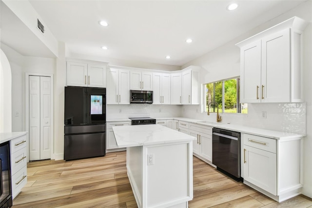 kitchen with light wood-type flooring, a sink, white cabinetry, and black appliances