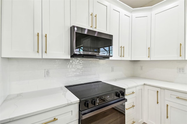 kitchen with tasteful backsplash, stainless steel microwave, white cabinetry, and black electric range oven