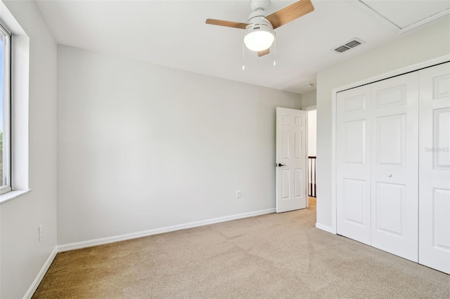 unfurnished bedroom with visible vents, baseboards, a closet, and light carpet