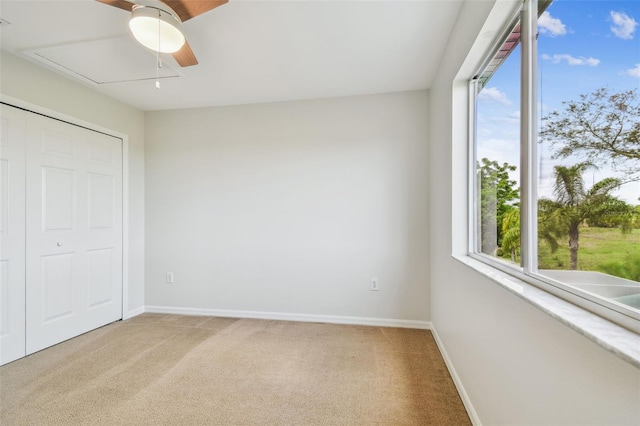 unfurnished bedroom featuring baseboards, a ceiling fan, attic access, and light carpet