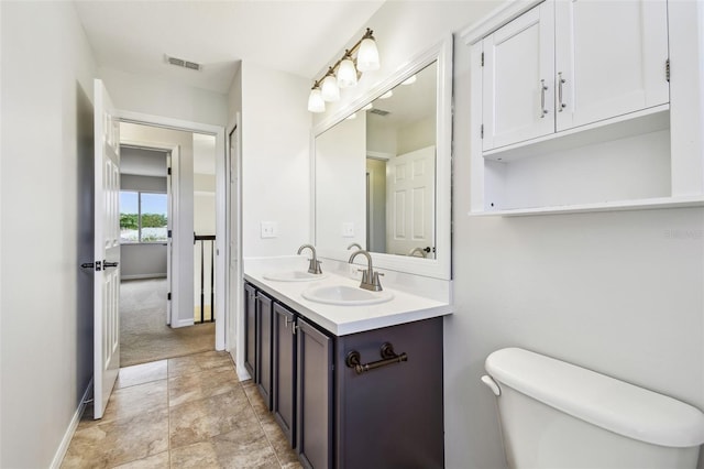 full bath with a sink, visible vents, toilet, and double vanity