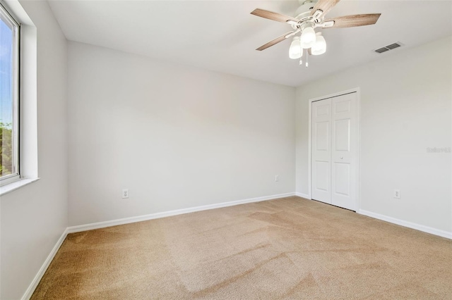 spare room featuring visible vents, baseboards, a ceiling fan, and carpet