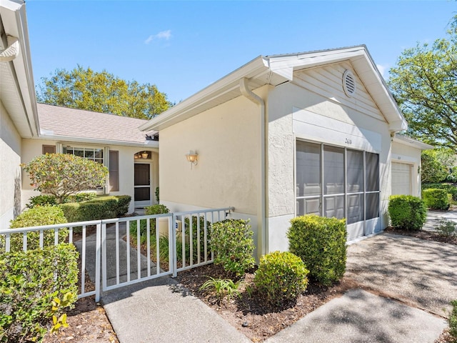 exterior space featuring fence, a garage, and stucco siding